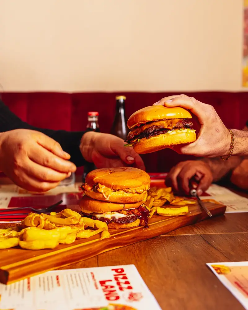 Due smash burger presi in mano al tavolo da Pizzzland